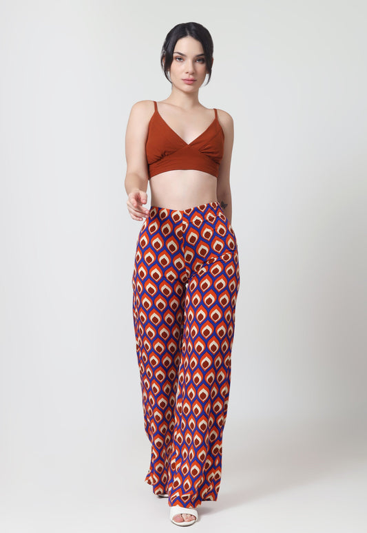 Woman wearing a brown crop top and patterned pants on a white background